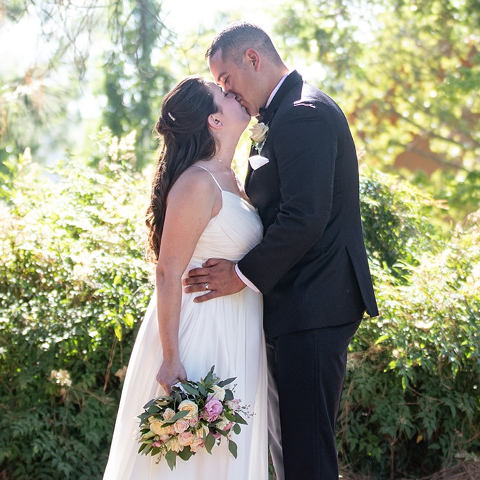 wedding couple sit behind a giant wedding garland